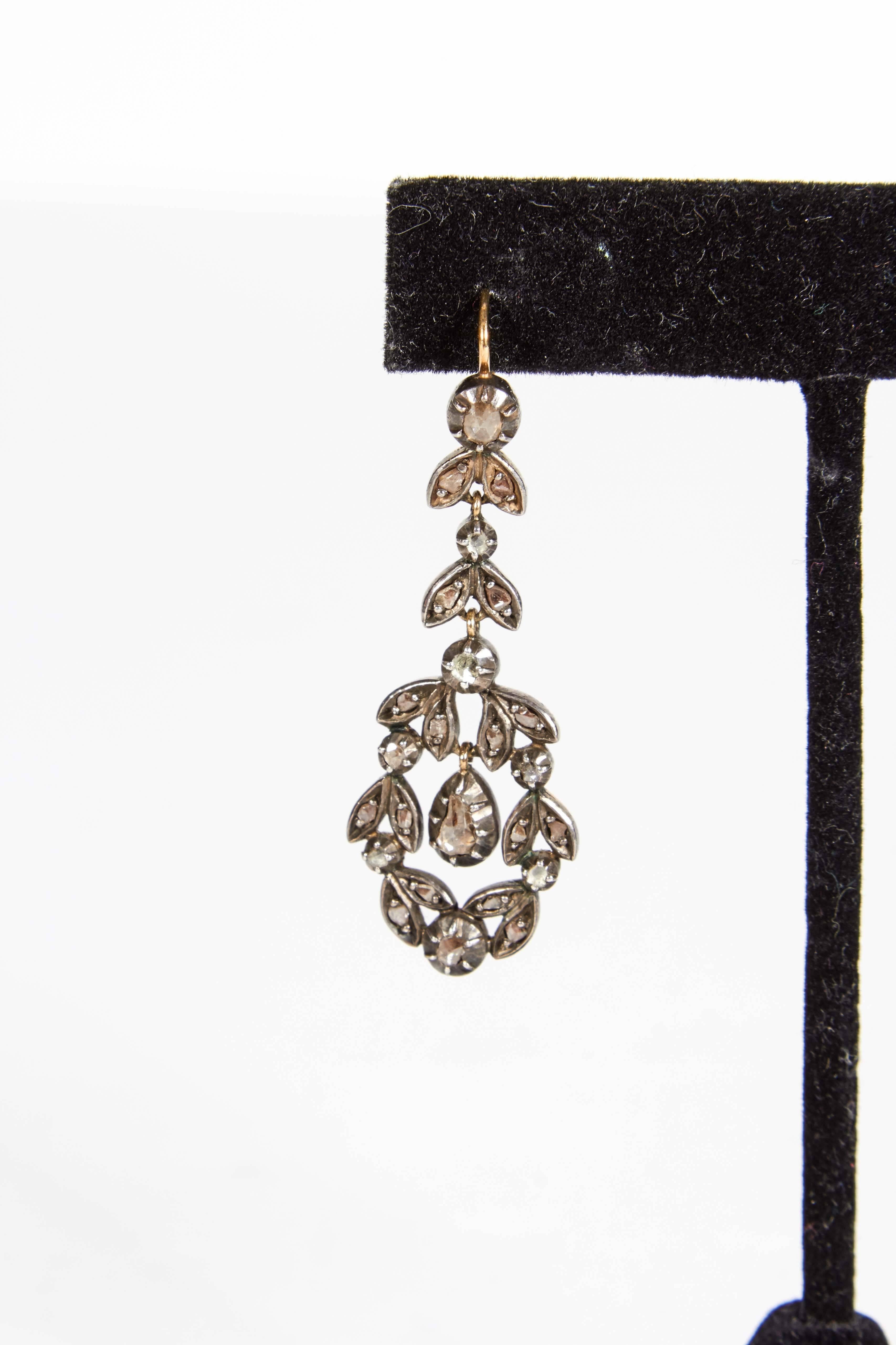 A lovely and graceful pair of classical double leaf design Georgian gold, silver and rose cut diamond pendant earrings. Circa 1830 / 1840. The front of each earrings is silver with the lever backs, wires and backs of earrings in 14K gold.