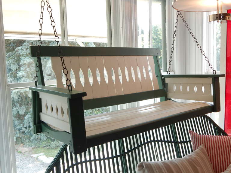 Charming wooden porch swing, freshly painted in green and white exterior paint.