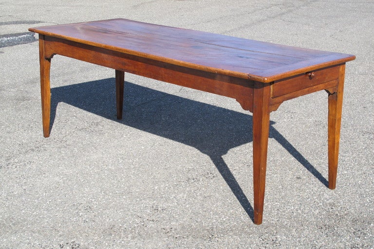 A cherrywood French 19th C Farmhouse table with a drawer at one end, on simple tapered legs, and breadboard ends.
24