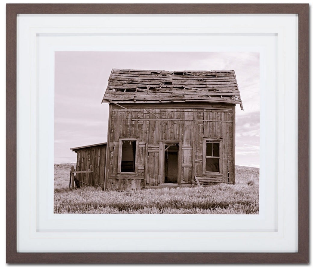 Matted print of an abandoned farmhouse in a brown wood frame. Please contact for current availability.