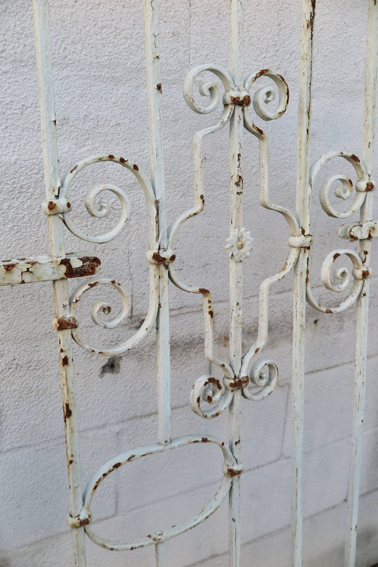 A pair of French wrought iron gates with old white paint.