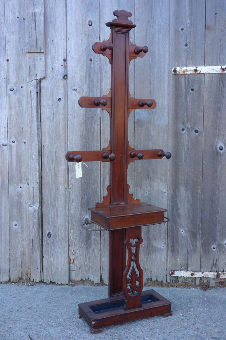 Mahogany carved hall stand with eight coat hooks, opening compartment and umbrella stand.