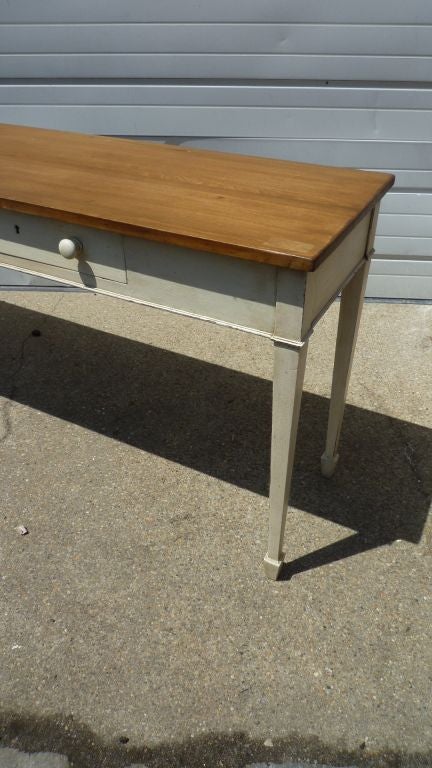 A long and narrow console table with 2 drawers, painted base and waxed top.