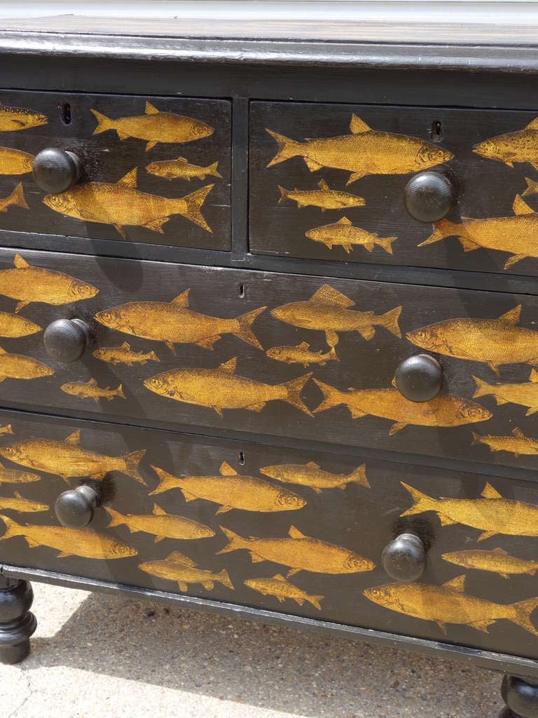 Three drawer chest with gold fish design in black decoupage, on turned feet.