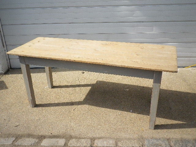 A charming table with a grey painted base, tapered legs and a raw pine top. Very stable.