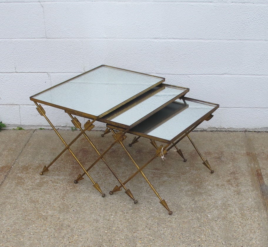 A smart set of nesting tables with glass/mirrored tops. Cross metal legs in the style of arrows, in gold paint. sold as a set only.