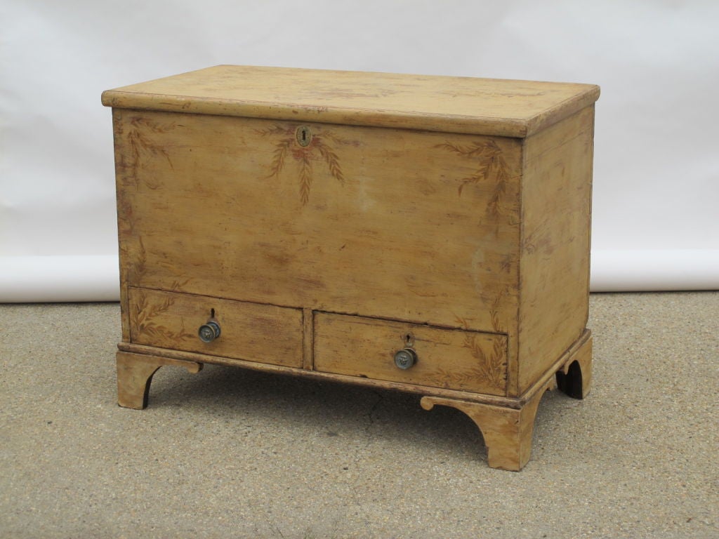 A large English pine trunk with 2 lower drawers and brass pulls. Hand painted detail of leaves at each corner to the front, and a brass lock (no key). Carved brackets lift this box to above avergae height. Wonderful end of bed storage.