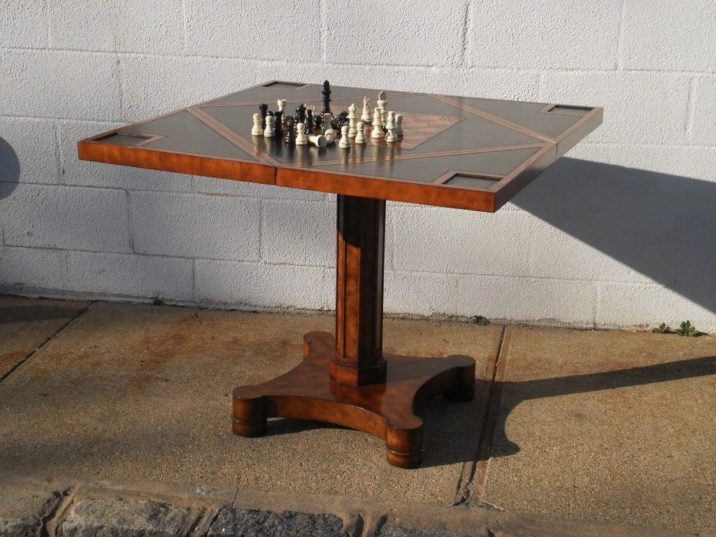 A walnut burl veneered and cherry crossbanded games table, the closed table with a circular quartered top, each section folding over to create a square games table with an inset hand tooled leather playing surface, chessboard inlaid centre and