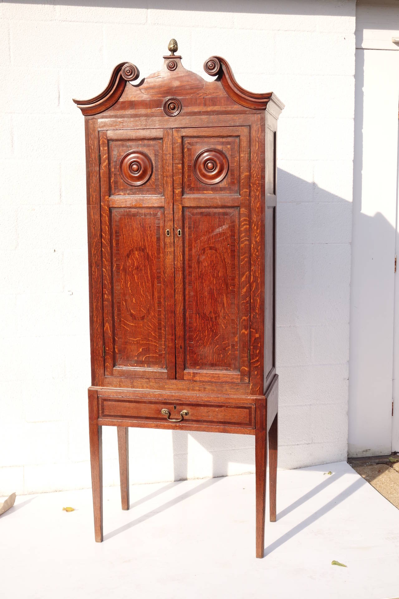 Unusual Hepplewhite style or late Georgian style cabinet with carved cornice, brass artichoke cornice piece, two inlaid cabinet doors, one lower drawer, raised on tapering square legs. Please contact for current availability.