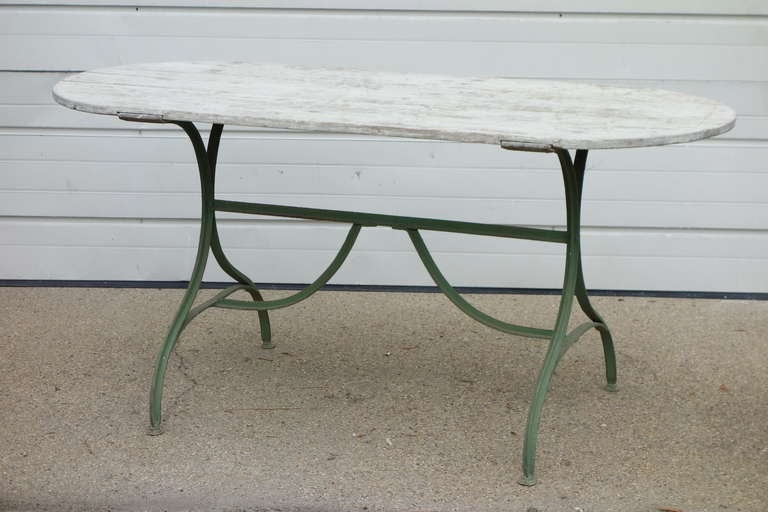 A French dining or occasional table with painted iron base and limed wooden top, with D ends.