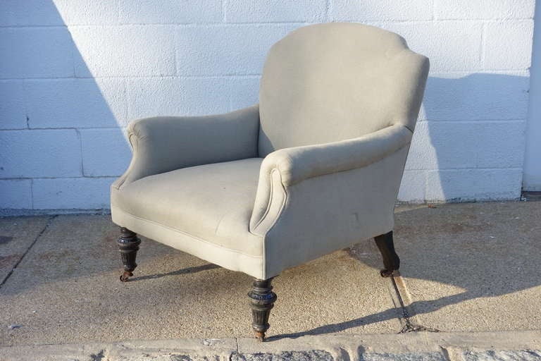 Newly upholstered club chair, English circa 1920. Fabric: grey linen.  Hand carved wooden legs on original casters.