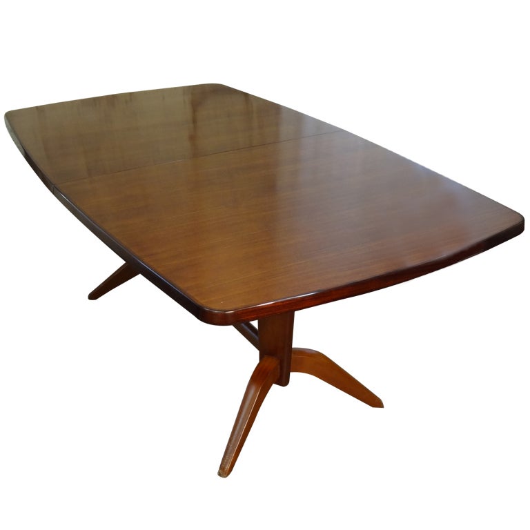An extending dining table produced by Gordon Russell, Ltd., in the Russell workshops in England, ca.1962. The table's design executed by his brother, William H. Russell. Labeled.  The 19.75