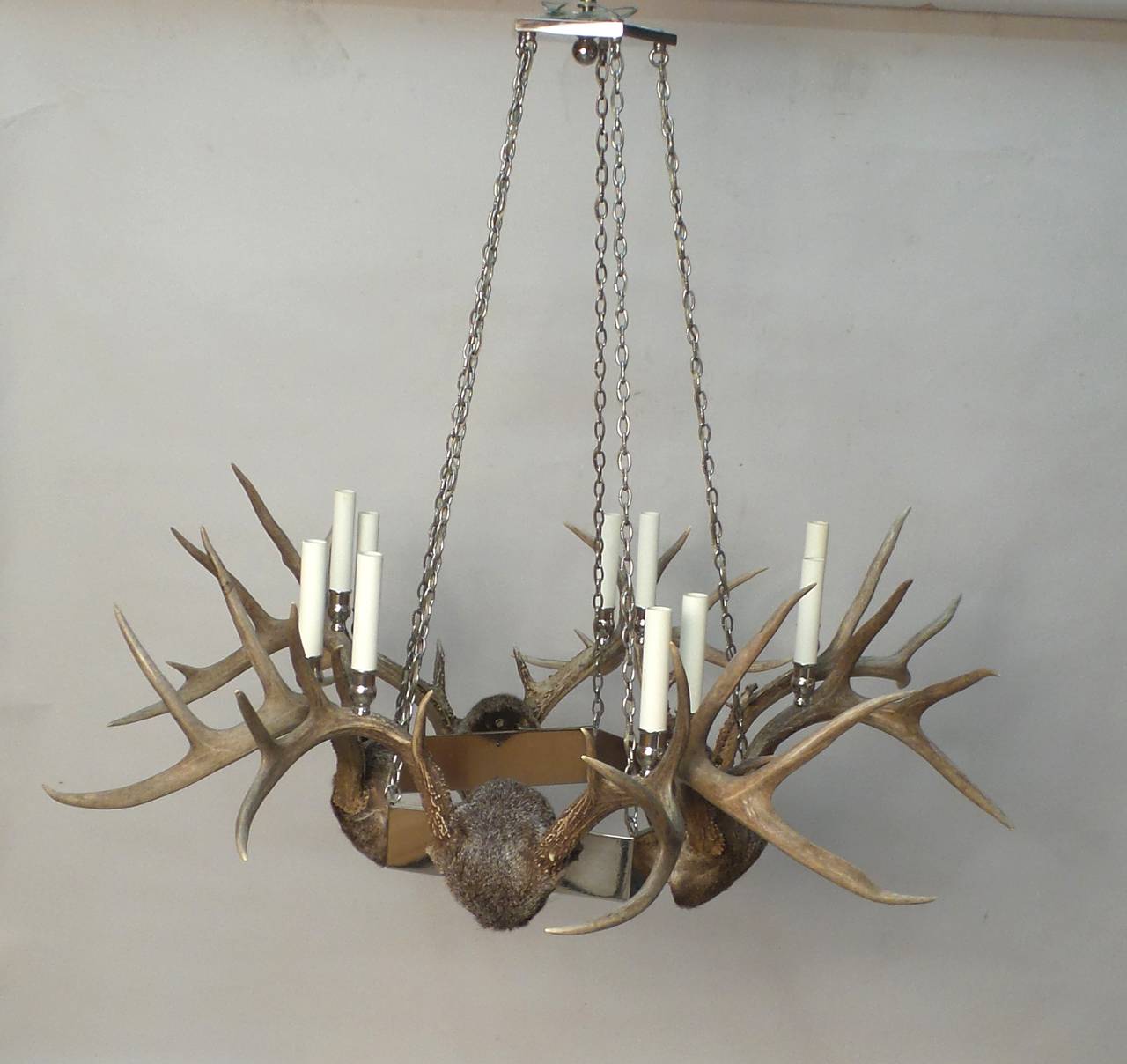 A modern chrome and natural deer horn pentagonal chandelier having eight lights. 31.5” H x 35.5” diameter. Recently professionally rewired with eight candelabra base sockets. We recommend that client’s own electrical contractor verify all electrical