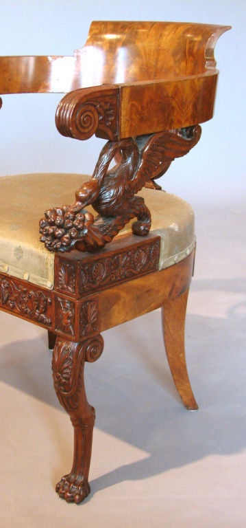 A rare early 19th Century Neapolitan desk chair executed in mahogany and mahogany veneer, the back splat and blocks over the animal form front legs carved with trophy motifs, the arm posts in the form of swans astride cornucopia.  Ca. 1815.