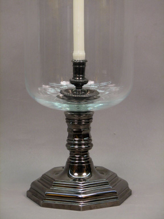 A large Louis XIV style hurricane lamp having a black nickel-plated octagonal body fitted with a handblown glass shade having a rolled lip.