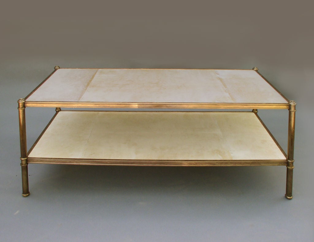 A coffee table edition of the etagere design originally made by Frederick Victoria for Billy Baldwin's client Cole Porter, in a patinated brass frame with custom extruded molding and holding parchment covered shelves. Parchment treated with heat and