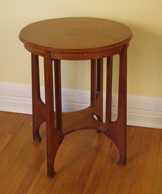 A Belgian circular side table of unusual Secessionist inspired design executed in oak with four legs unified by a stretcher, circa 1900.