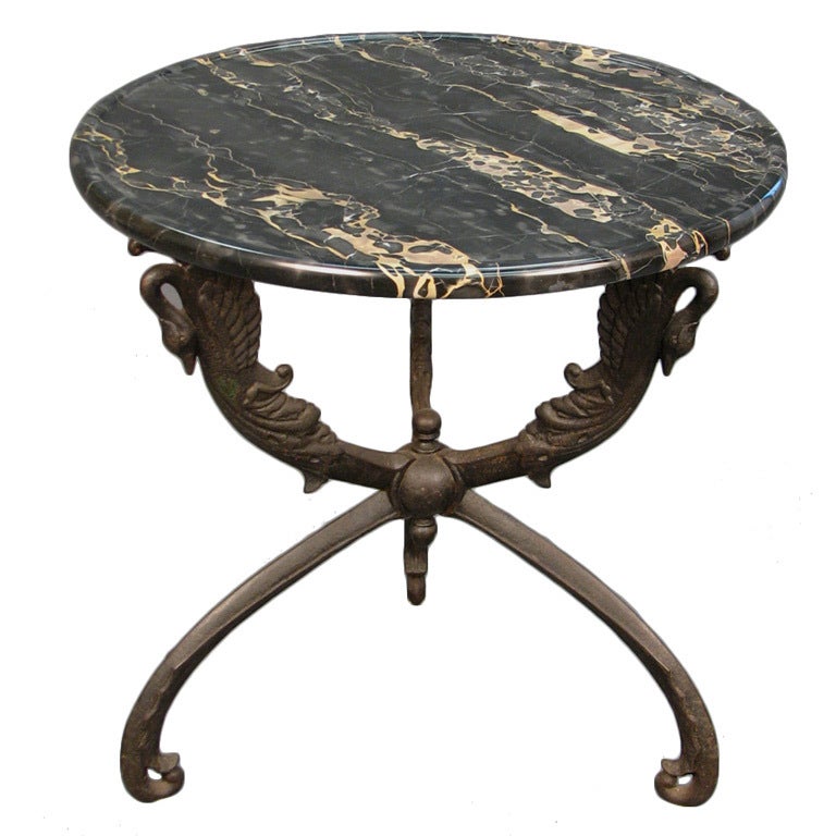 A 19th century tripodal gueridon executed in cast iron. The legs terminating in swan figures, supporting a beautiful, thick black and gold Portor marble top having a recessed surface, France, circa 1860.