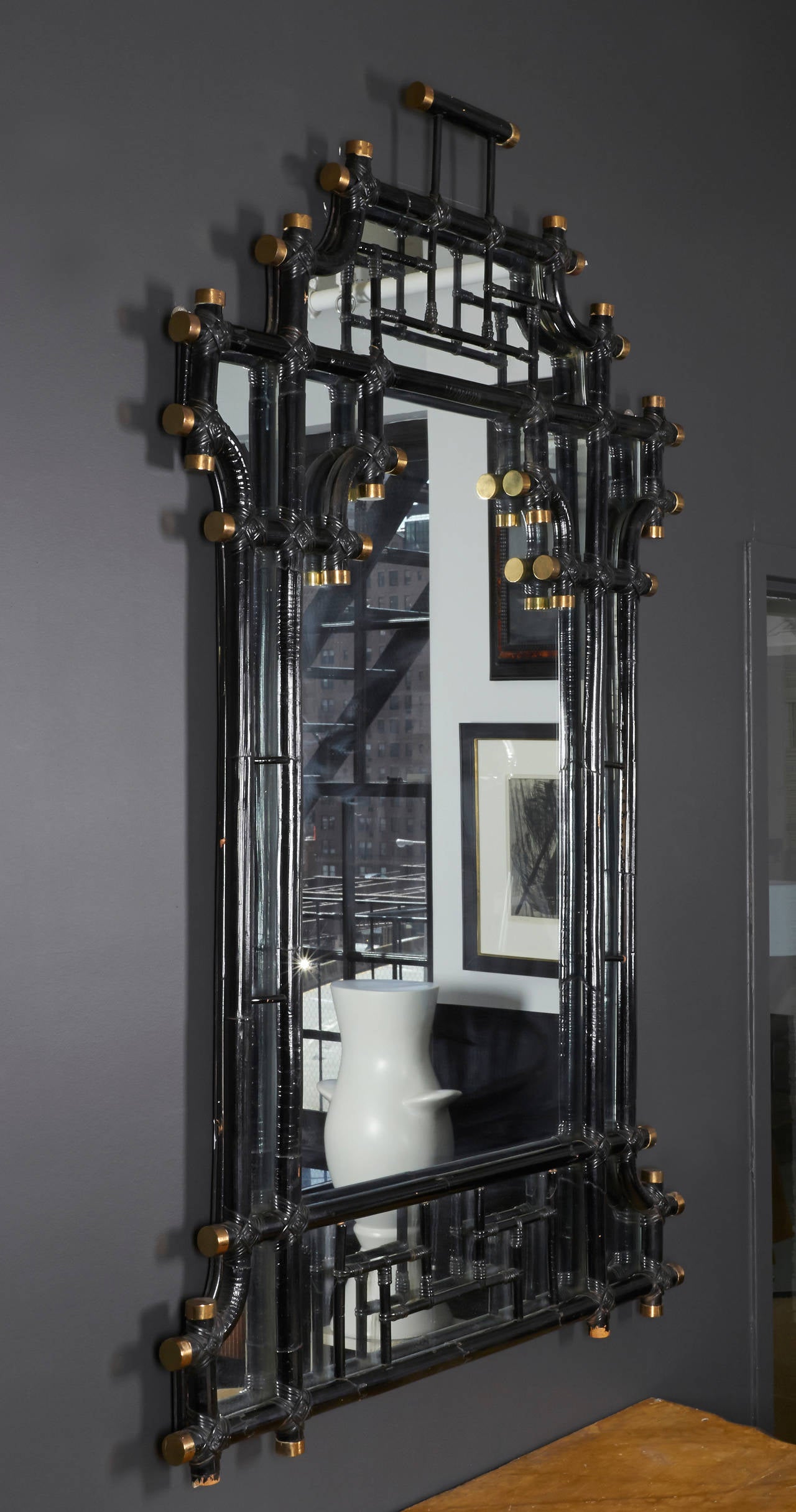 This mirror is a true stunner, beautifully made by the famous house of Jansen.
It has hand wrapped joints of black bamboo with brass caps at the end of each joint. All details are in very good condition and the black shiny frame is deep and rich.