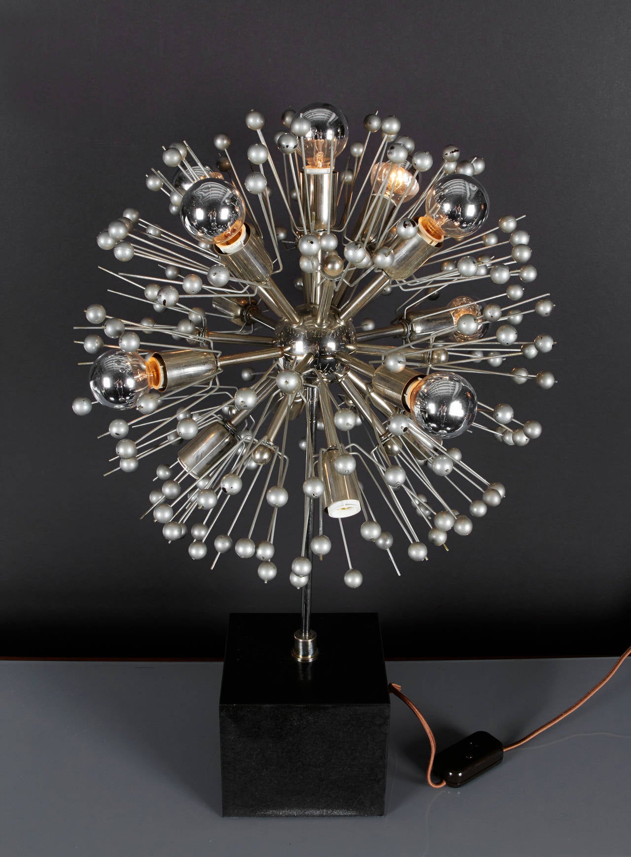 An Italian Sputnik table lamp with 16 lights mounted in to a solid balck marble base, the switch has a dimmer for ambient lighting.