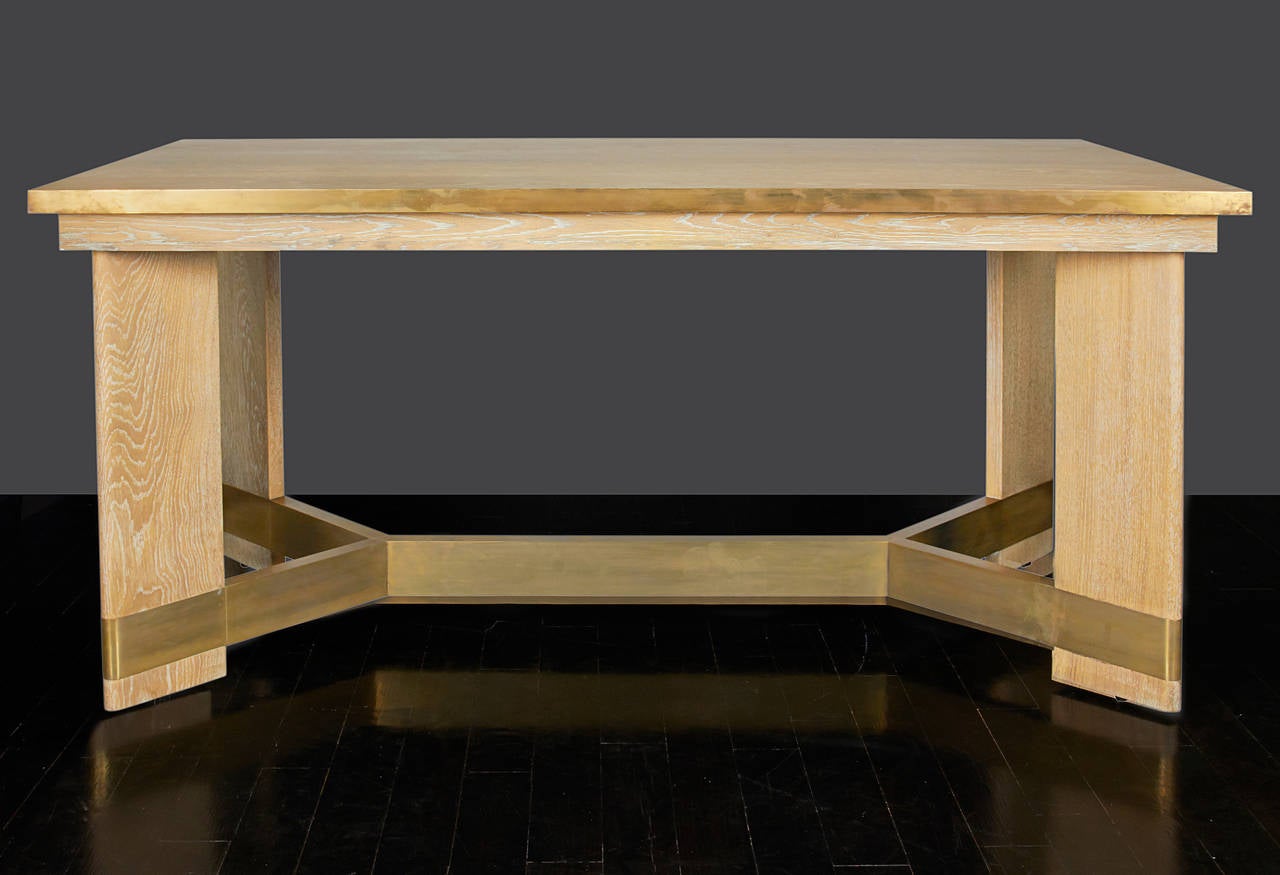 In the style of Jean Michel Frank, a cerused oak desk with a brass banded edge detail around the top - a brass stretcher supporting the four solid oak legs.