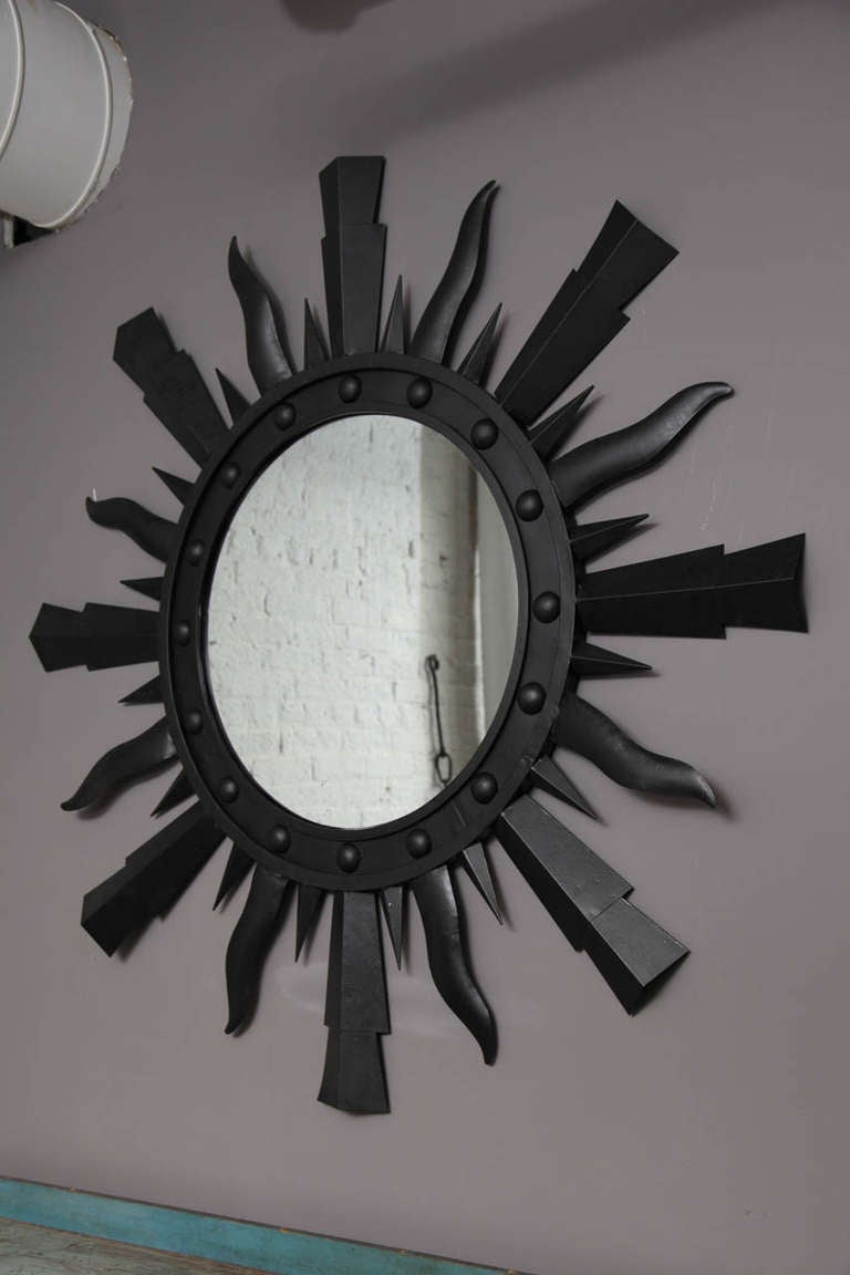 A metal starburst mirror painted black
