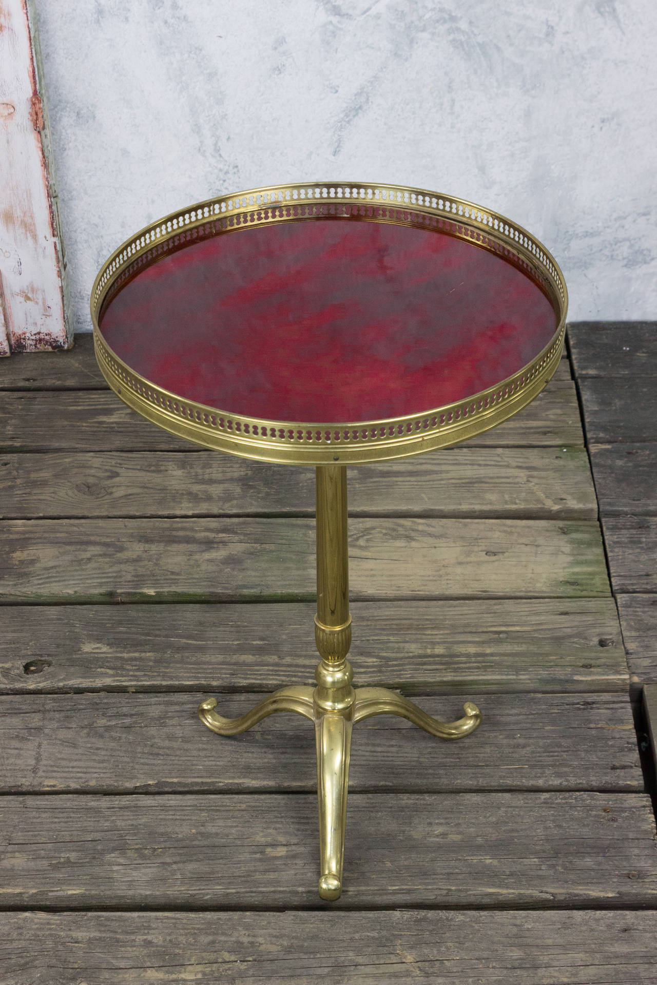 Small brass round end table with red acrylic inset on tripod base.