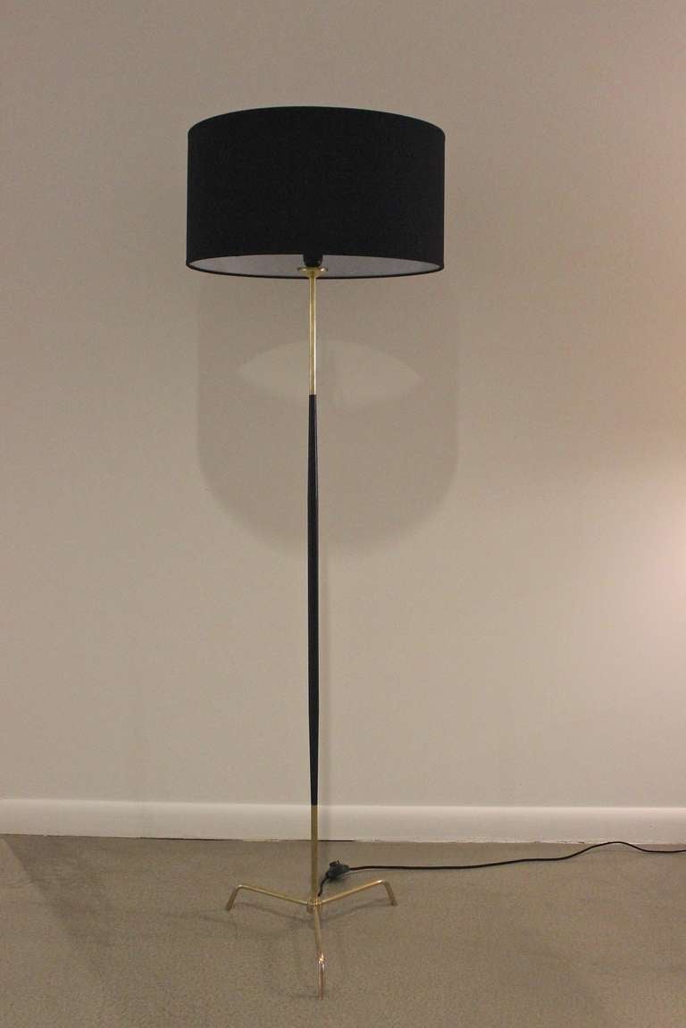 Sleek Stilnovo brass floor lamp with tripod base and black drum shade. Lamp was recently rewired and features a black foot switch.