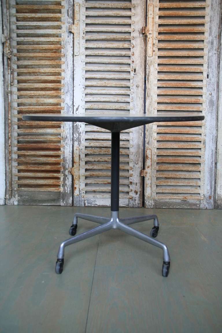 American Mid-Century Modern dining table with cast aluminum base with wheels. The top has a laminate surface.