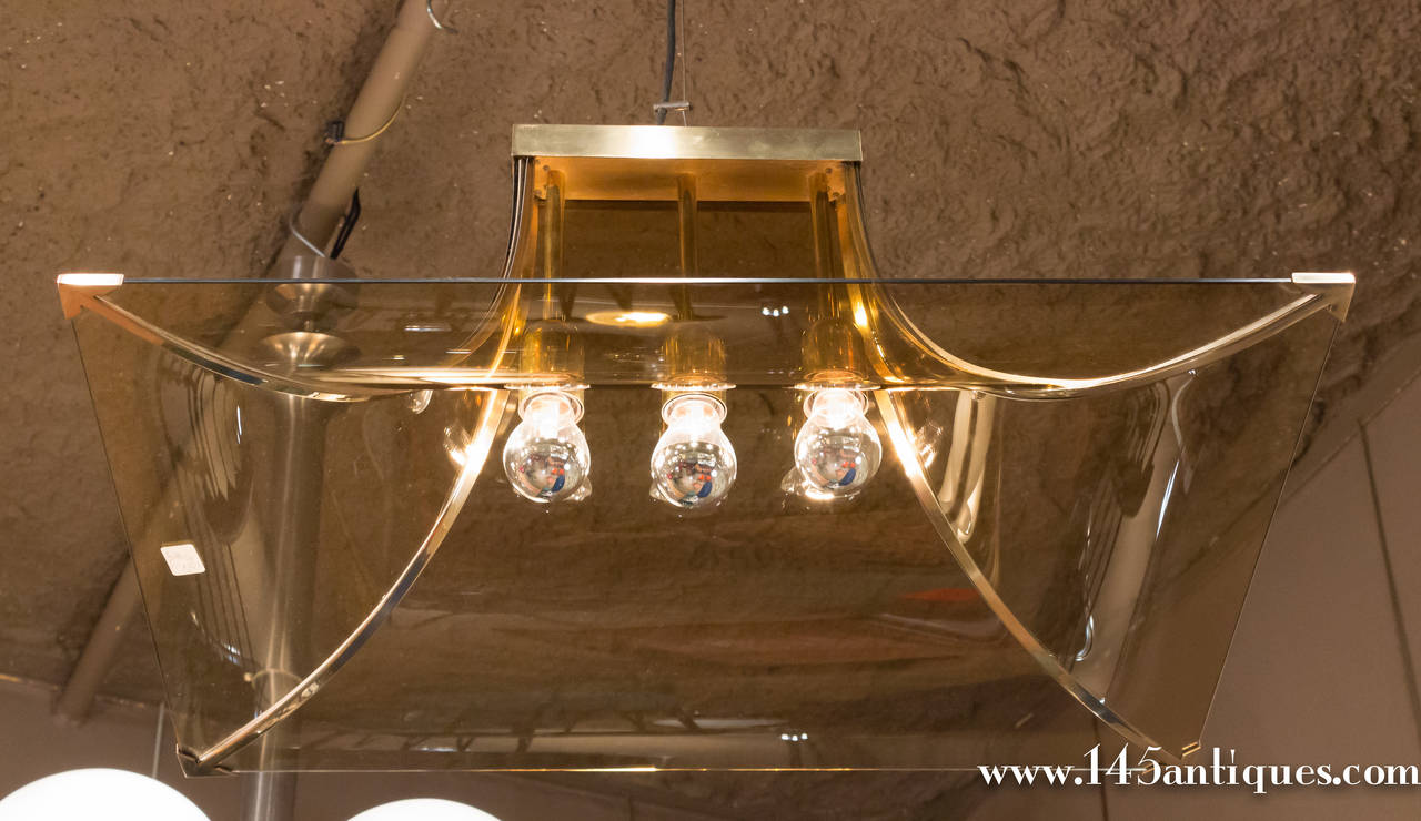 Very unusual chandelier, Italian, 1970s, in the style ofFontana Arte. The brass frame is surrounded by curved glass, and is fitted to accommodate three Edison bulbs.

Item located in France, please allow 4 to 6 weeks delivery to New York City.
