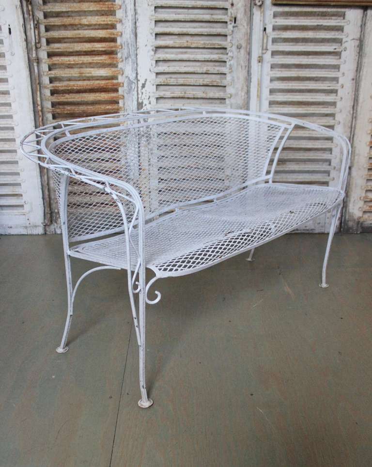 White metal garden bench with wire mesh seat and back. 