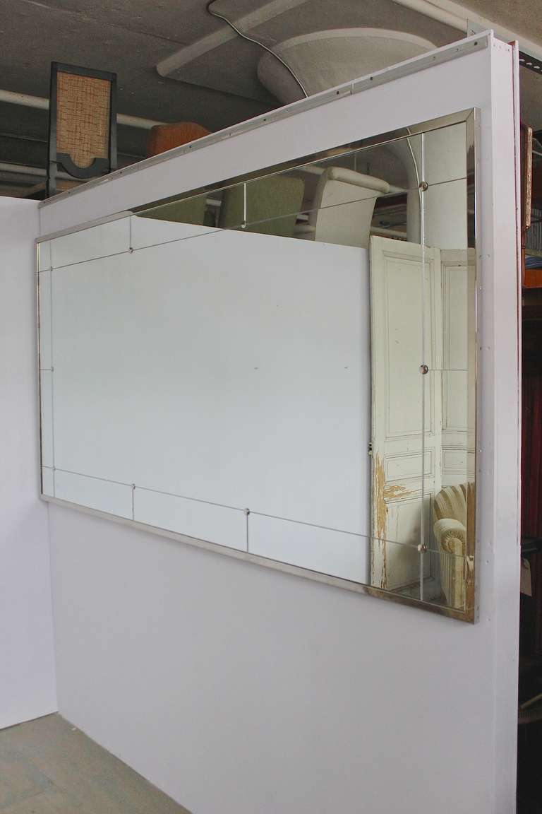 Large horizontal mirror in nine sections of mirror surrounding a large central panel of mirror, mounted in a nickel-plated frame.