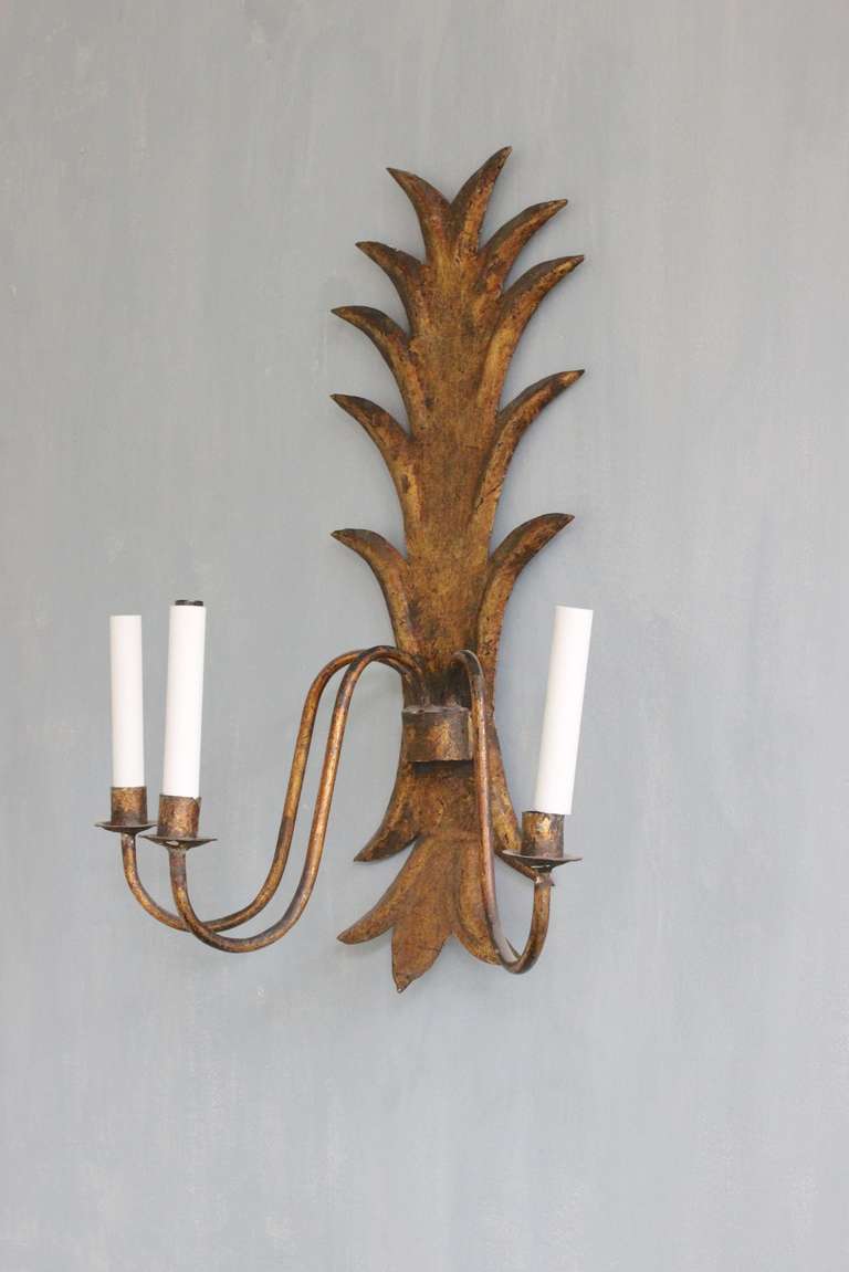 An unusual 1950s Spanish gilt metal three-arm sconce wired for candelabra bulbs. This large Spanish gilt metal sconce is a stunning piece of vintage lighting. The intricate details of the sconce are indicative of the quality of Spanish craftsmanship