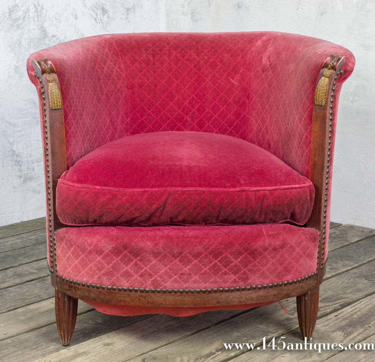 Pair of French Art Deco Armchairs in a raspberry velvet with a hatch cross design.  The legs are fluted with a gold tassel design on the arms and decorative nailheads.