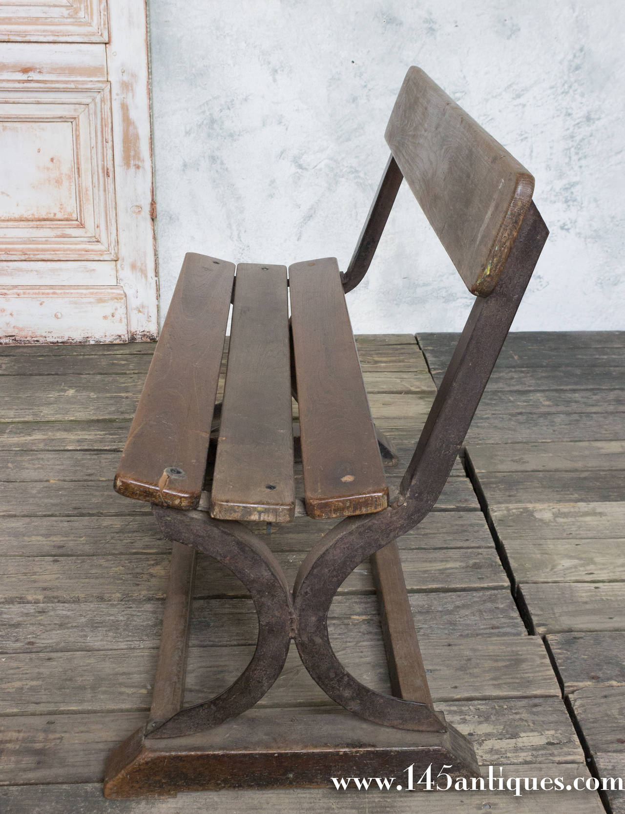 Small park bench with wood plank seat and back on an iron frame base, France, circa 1900.