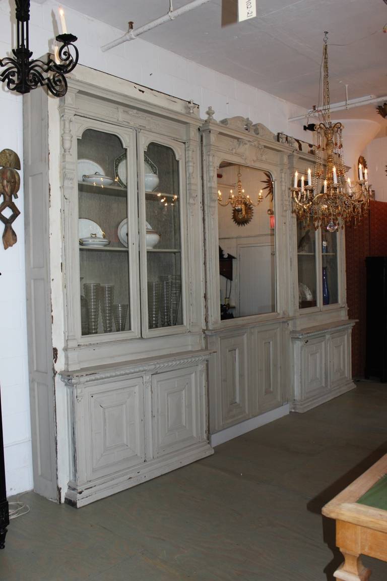 This  very large French boiserie most  likely came out of  a French  chateau.   It is in 3 separate sections that can be joined together. The two end sections   have  double glass doors  with shelves  on the upper part and enclosed  storage on the