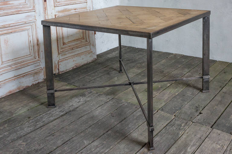 Square table with hand crafted iron frame and wood parquet top.