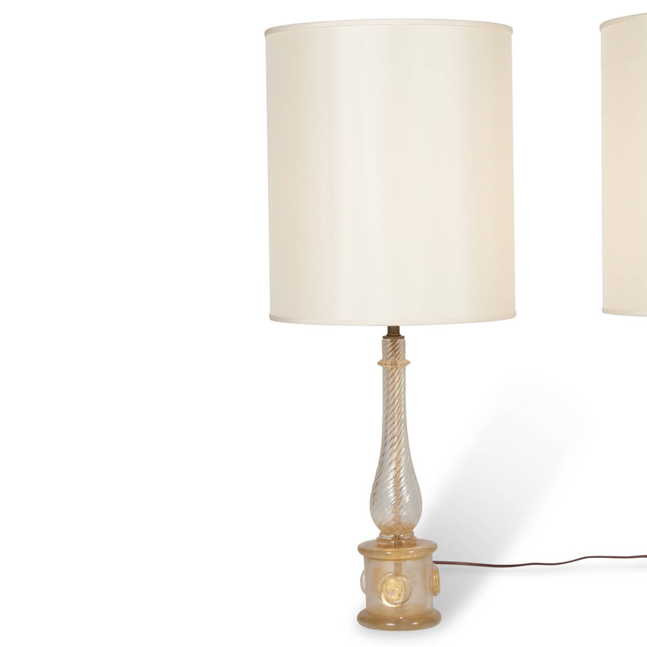 Pair of glass column lamps with applied discs at base, the glass clear, spiraled, and with gold inclusions, by Barovier e Toso, Italian, 1940s. Measures: 4 1/8” D base 14.5” D shade at widest, 29.75” H. 
    
    