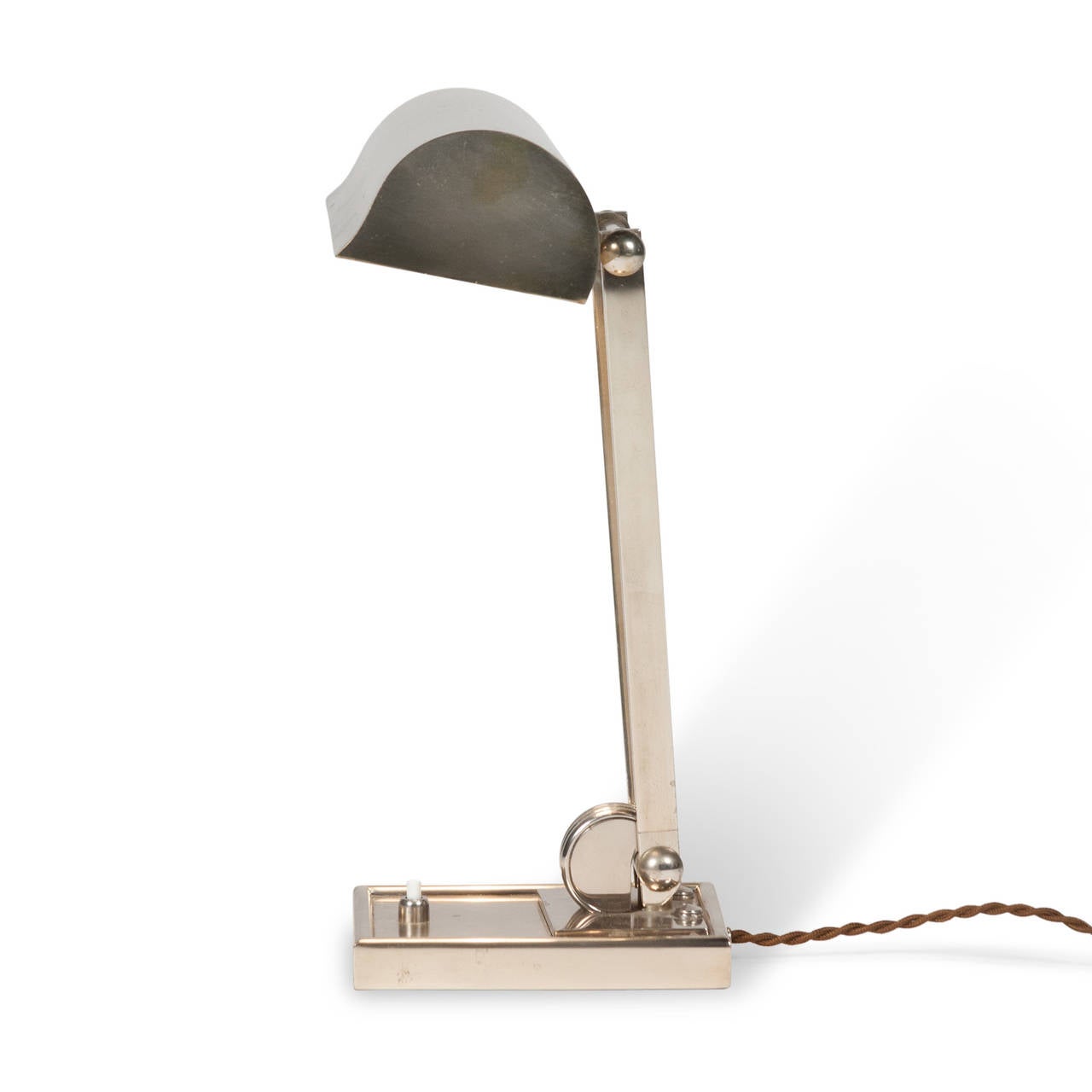 Nickel desk lamp, the pivoting shade supported by two angled rods, which themselves pivot on the square base, French, 1930s. Measures: 9 3/8” W, 5.75” D, 14” H.

  