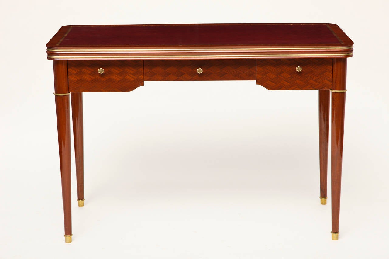 Walnut marquetry writing table with gilt bronze accents and a leather writing surface, which opens into a felt top game table, by Maison Leleu.

Numbered: 24688.

Depth when fully extended as game table: 43.25