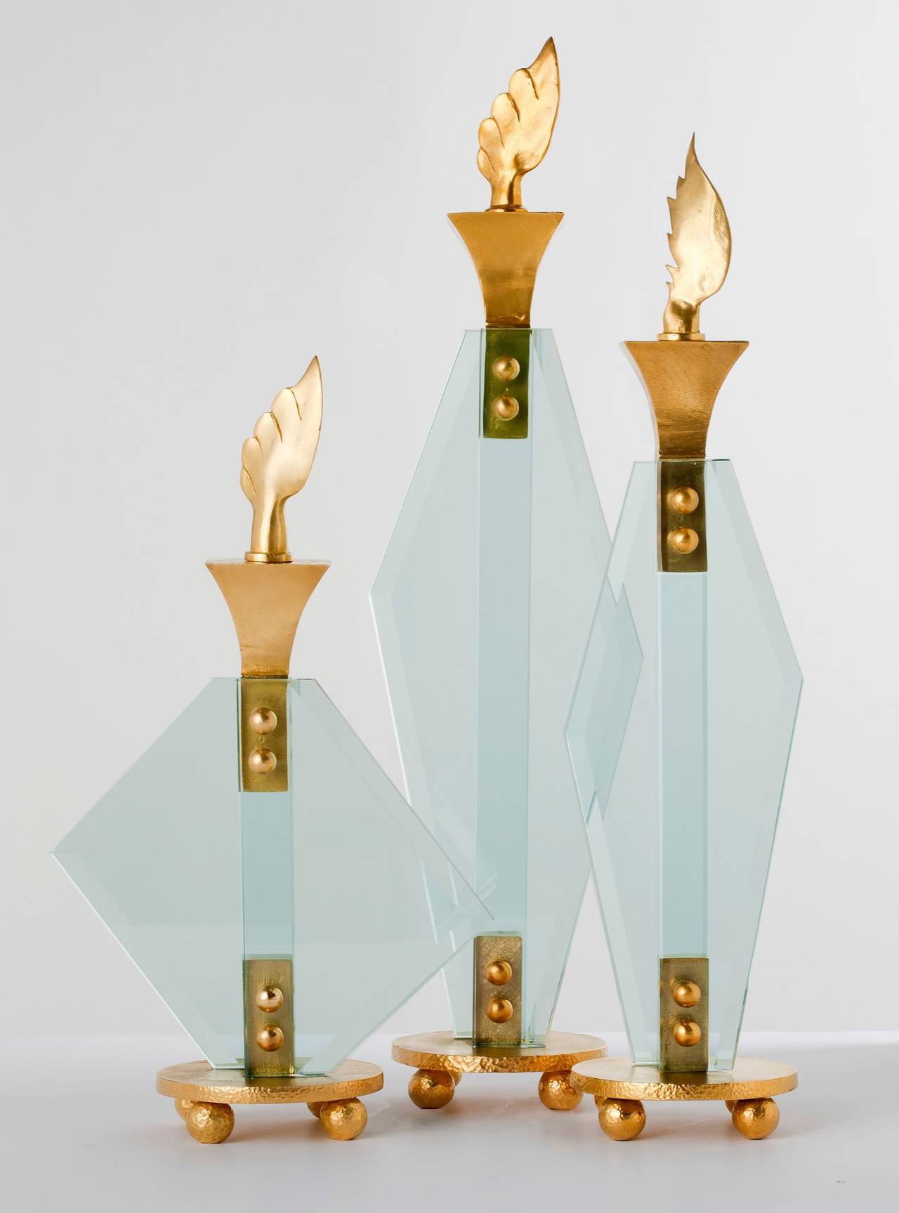 Gilt bronze and glass candlesticks with removable decorative flame finials, by Aldus. Each size is an edition of 100.

Small: Height: 11.5