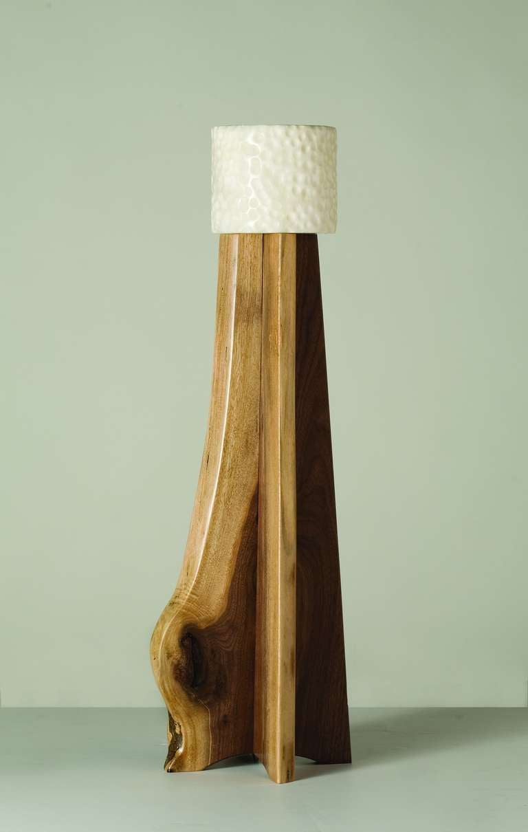 The Copiaco lamp, carved of two pieces of black walnut that have been sanded so as to be smooth to the touch, is topped with a cylindrical alabaster shade.