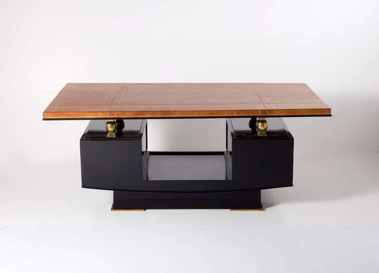 An Art Deco coffee table with a black lacquered base, gilt-bronze ornaments, and a leather top with incised gold trim.  Each side of the base contains a compartment.

A similar table is illustrated in Maxime Old by Yves Badetz, Editions Norma,
