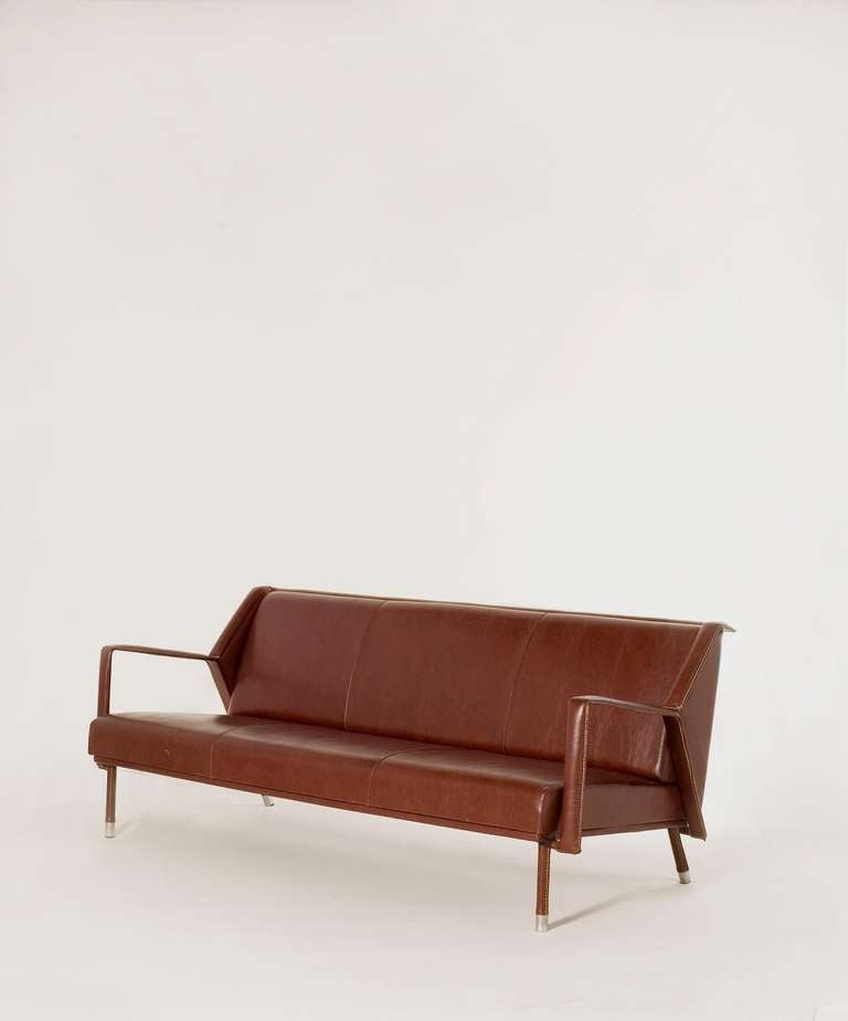 Sofa by Jacques Quinet in original saddle-stitched leatherette with chrome sabots

Provenance: This sofa was commissioned for the offices of Ciments Français, a cement factory in the north of France.

A similar sofa is illustrated in Jacques Quinet