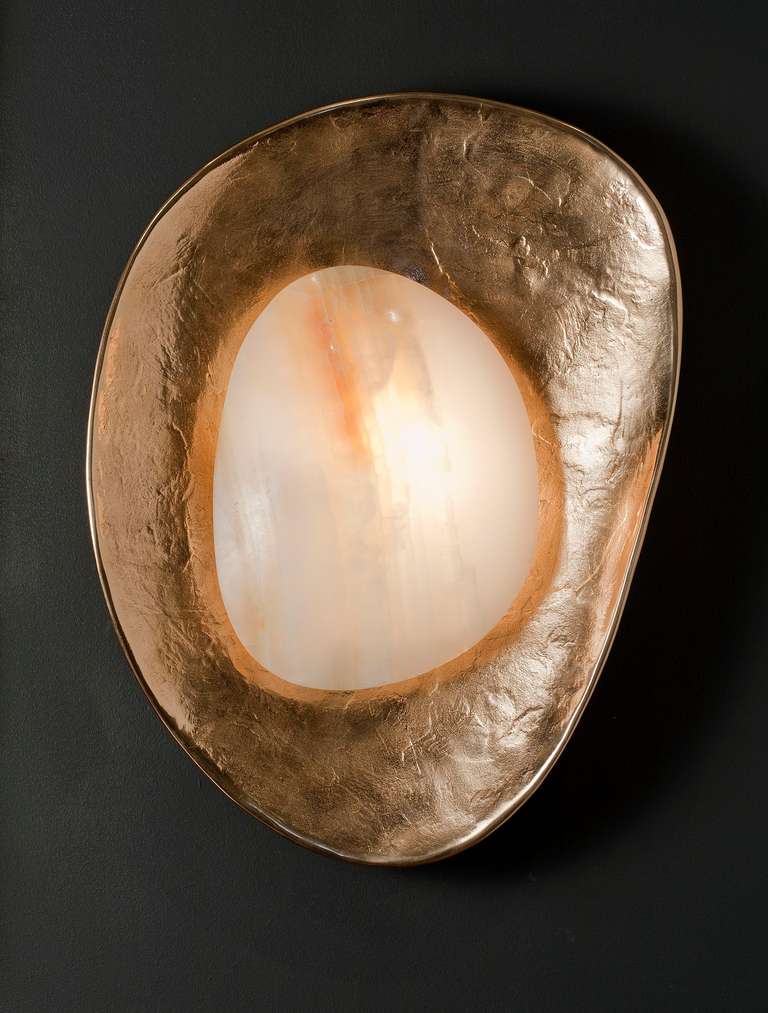 A concave, hand-hammered and patinated bronze sconce with illuminated onyx by Rome based architect Achille Salvagni, recognized worldwide for bringing together Italian craftsmanship and his passion for luxurious materials and traditional techniques.