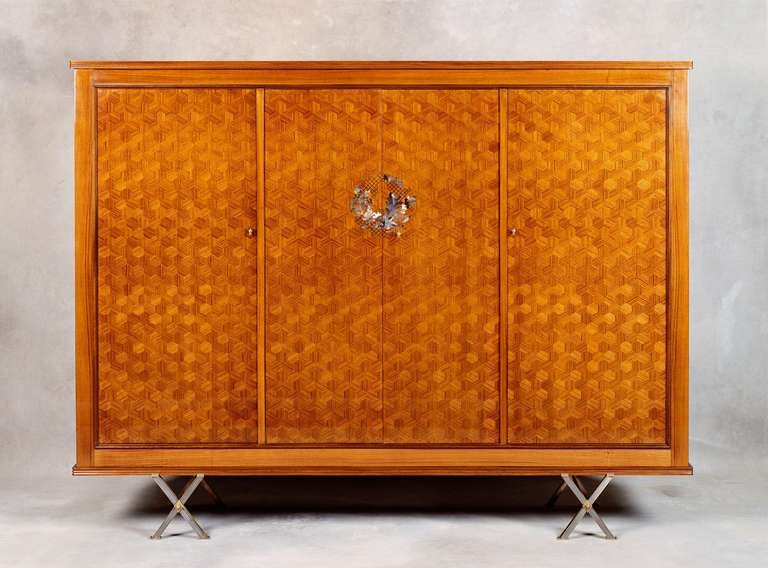 Fine four-door cabinet by Jules Leleu, with walnut marquetry and steel and brass legs. The design of the mother-of-pearl and ebony inlay is by Paule Leleu.

Numbered on back: 27933. 

For an illustration of an identical model, see:
Mobilier et