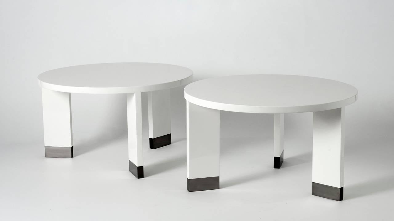 A pair of lacquered wood side tables with metal sabots by Jacques Quinet.