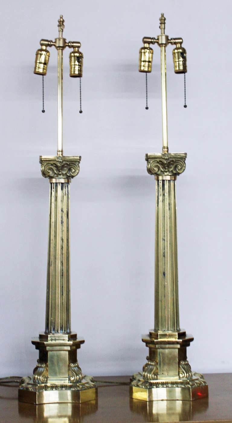 Stately pair of Messenger and Sons, London, brass “Corinthian Column” banquet lamp bases, second quarter of the 19th century, now mounted as table lamps, the fonts, chimneys and shades removed in the conversion, the interiors of the bases fully