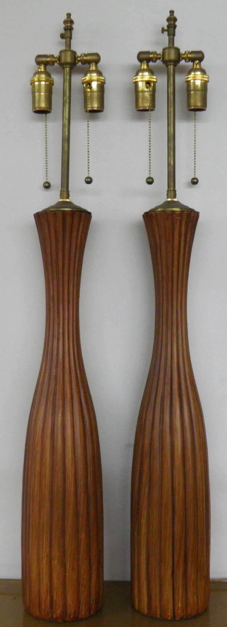 Tall pair of ceramic, faux-wood scored wood vases with lamp application.  The hardware is brushed Brass.  The dual sockets are individually controlled.  The finial post extends an additional three: if desired.

25 5/8