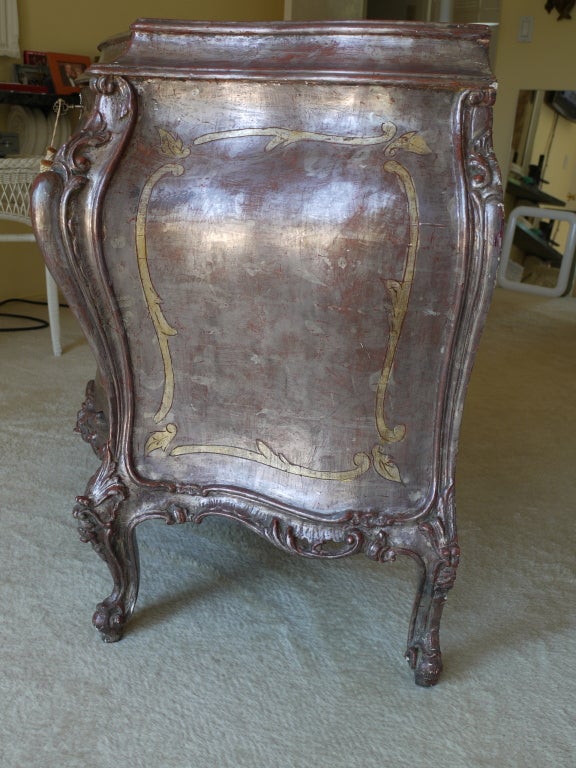 Italian Bombe 3 Drawer chest with silver leaf over deep reddish/brown gesso with silvered bronze handles with detail on top and face in palladium Gold.with beautiful carving